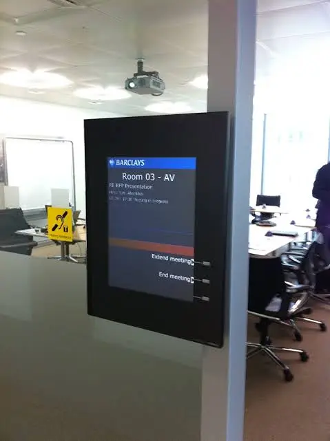 Um painel de sinalização digital instalado na entrada de uma sala de conferências