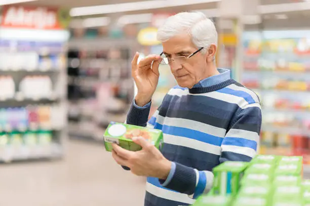 Homem lendo o rótulo de um produto no supermercado